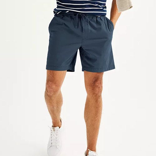 A man wearing navy blue shorts and white sneakers.