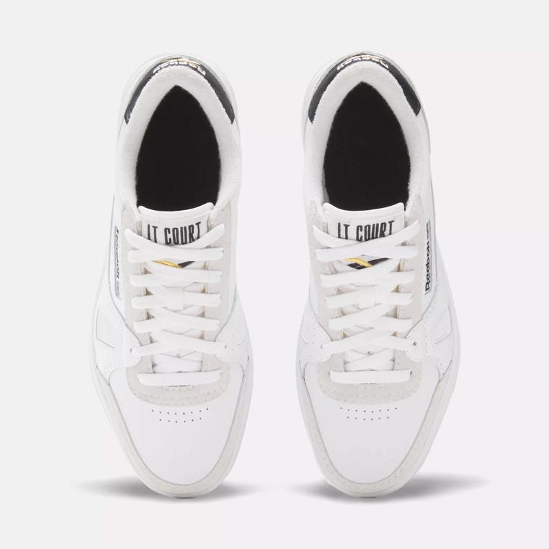 A pair of white low-top sneakers with lace-up fronts and black interior lining.