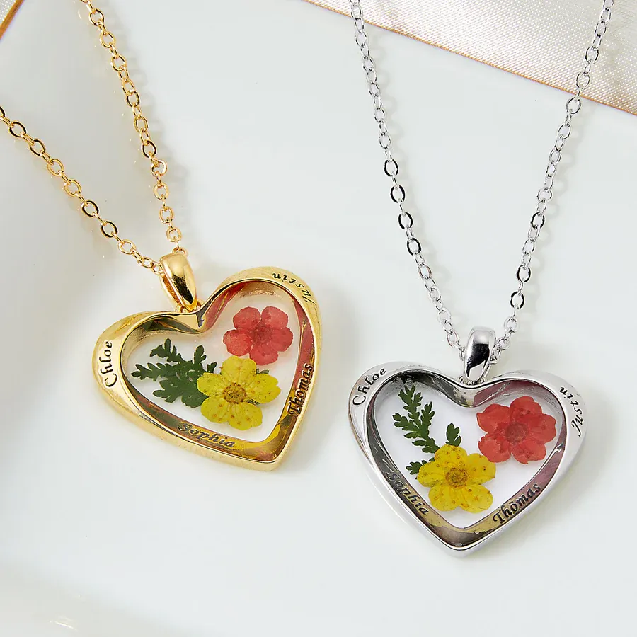 Two heart-shaped lockets with floral designs and personalized names on gold and silver chains.