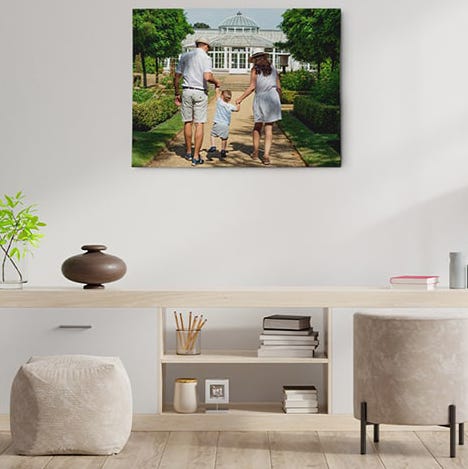 A framed canvas print is mounted on a wall above a minimalist wooden desk with storage shelves, complemented by a decorative vase and books.
