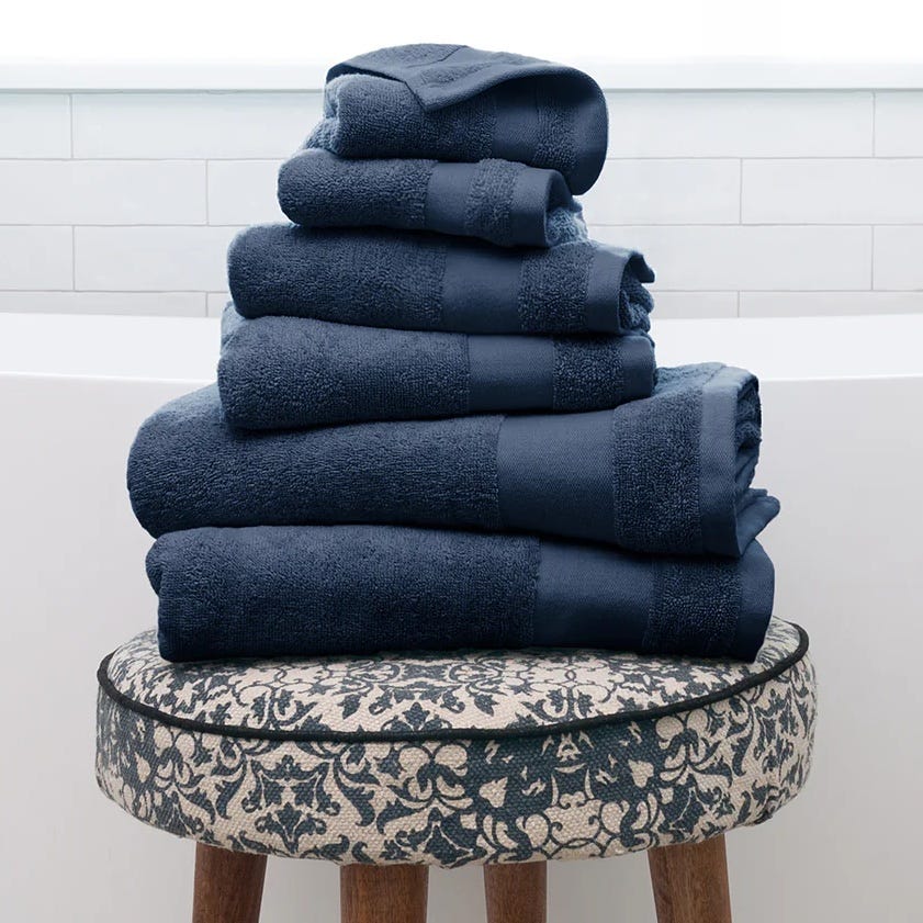 A stack of folded navy blue towels on a patterned round stool.