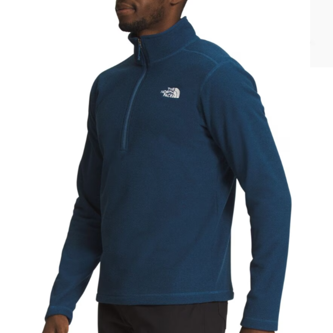 A man wearing a blue half-zip fleece pullover with a logo on the chest.