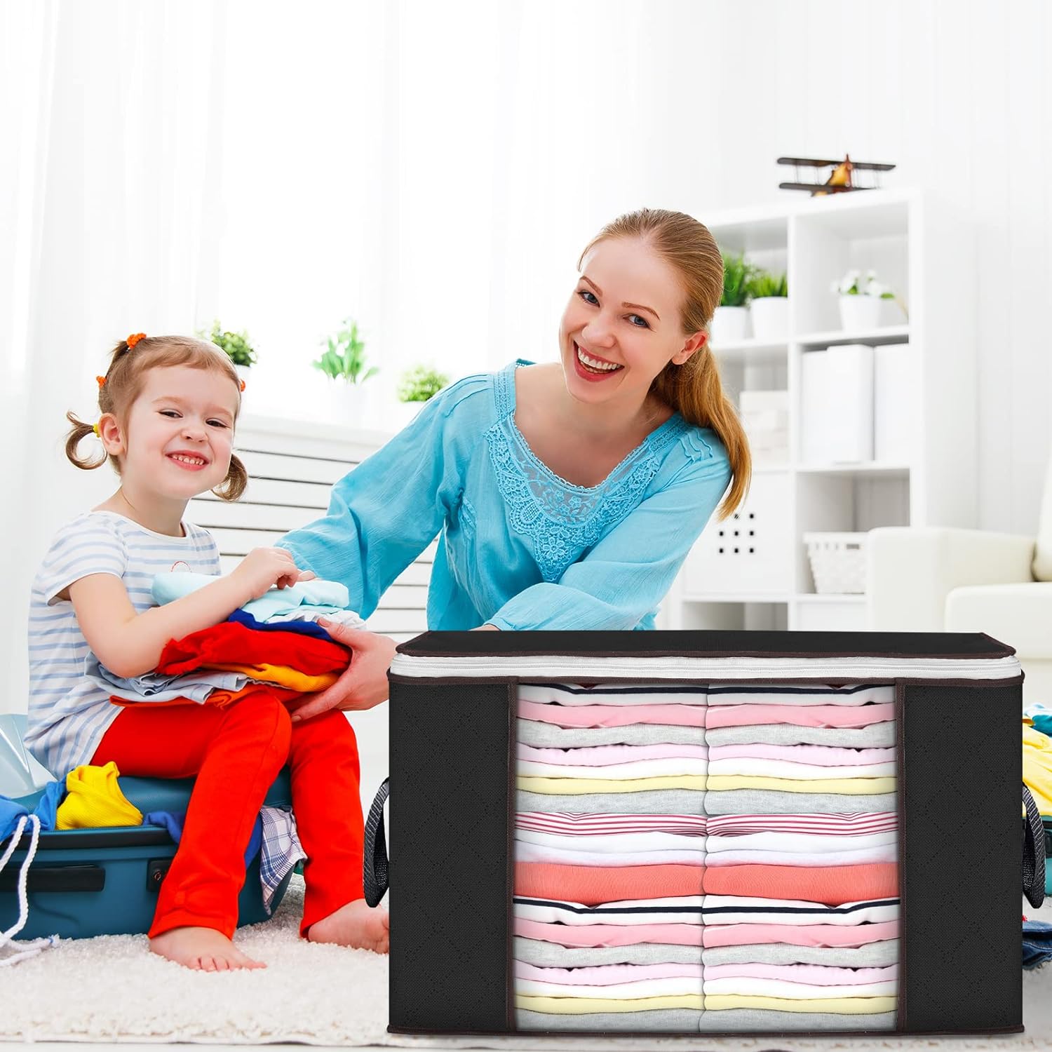 A woman and a child are smiling while sorting colorful clothes near a black storage organizer with neatly folded linens.