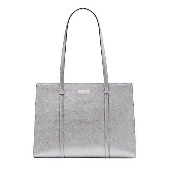 The Kate Spade Large Kenzie Metallic Tote features a sleek, rectangular design with long handles and a metallic silver finish, offering a stylish and spacious option for carrying essentials.
