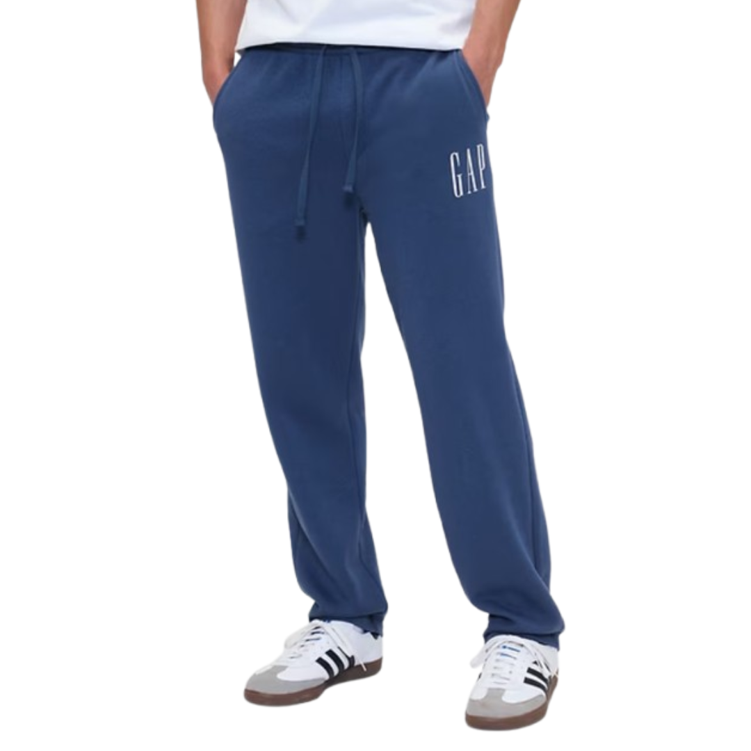 Blue sweatpants with \“GAP\“ logo on the left pocket area, paired with white sneakers that have black stripes.