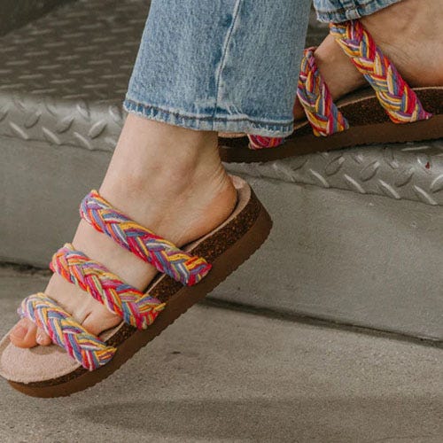 Colorful braided sandals worn with blue jeans.