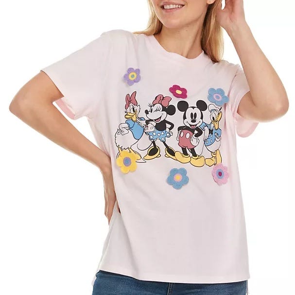 A light pink t-shirt featuring a graphic of animated characters with floral accents.