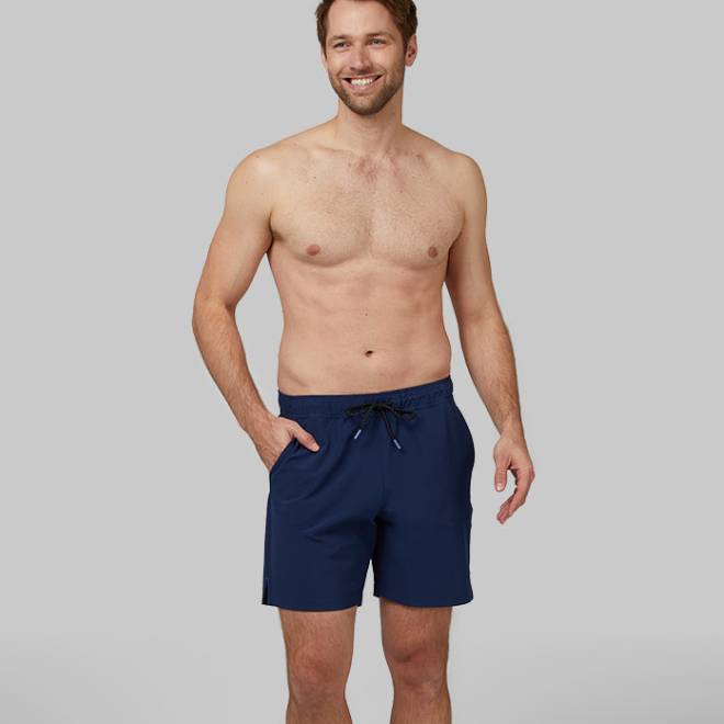 A man is wearing navy blue swim shorts with a drawstring waist.