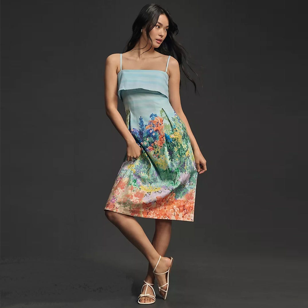 A woman in a strappy summer dress with a colorful, floral print design and white high-heeled sandals.