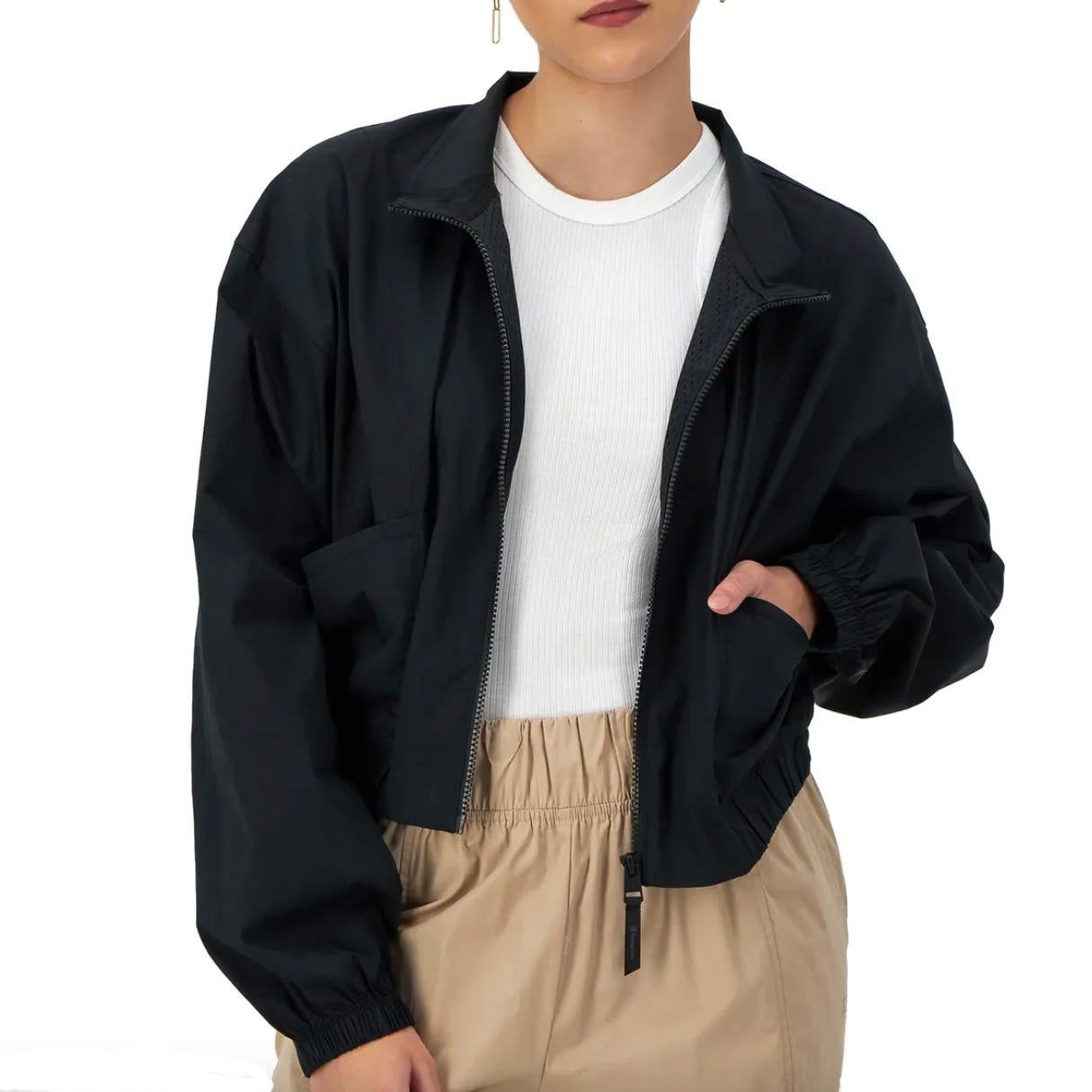 A person is wearing a black bomber jacket, a white crewneck top, and beige pants.