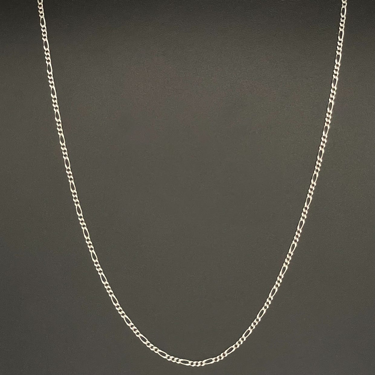 Silver chain necklace on a black background.