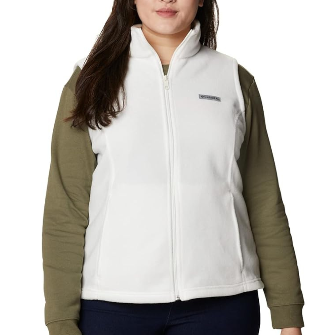 A woman wears a white fleece vest with a front zipper over a green long-sleeve shirt. The vest features a small logo on the chest.