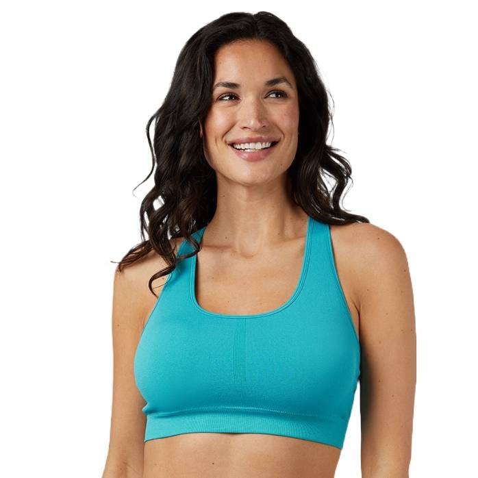 A woman wearing a turquoise sports bra with a racerback design. She is smiling and has long, wavy dark hair.