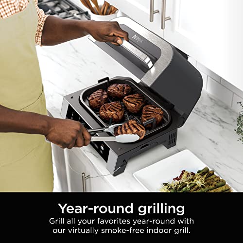 A person is using the Ninja Foodi XL indoor grill to cook steaks, highlighting the option for year-round grilling without smoke.