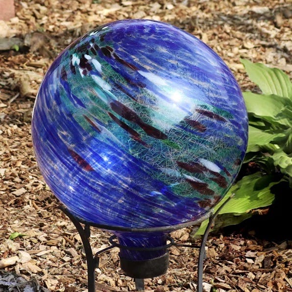 A blue and green patterned glass garden globe on a metal stand.