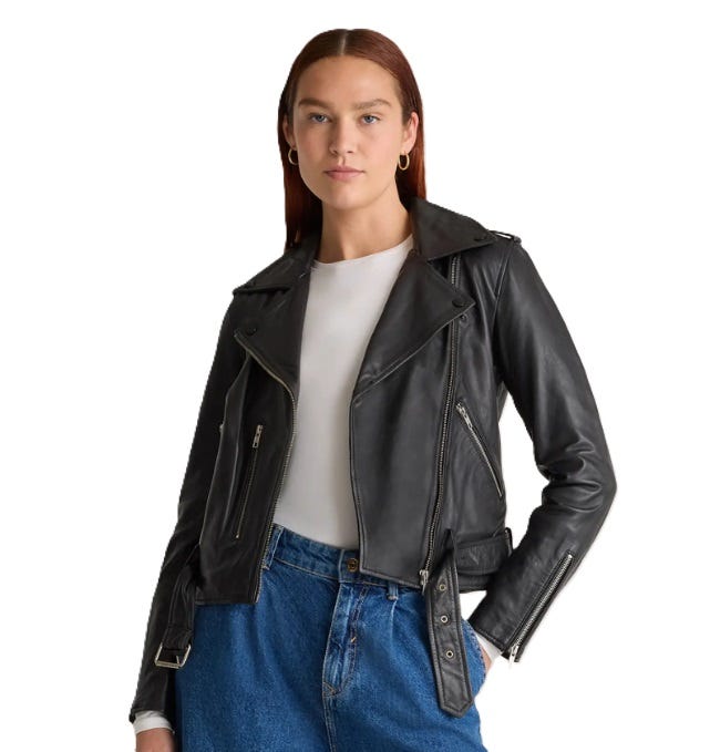 Black leather moto jacket with a classic design, featuring an asymmetrical front zipper, notched lapels, and zippered pockets. It is paired with a white shirt and blue jeans, offering a stylish and edgy look.