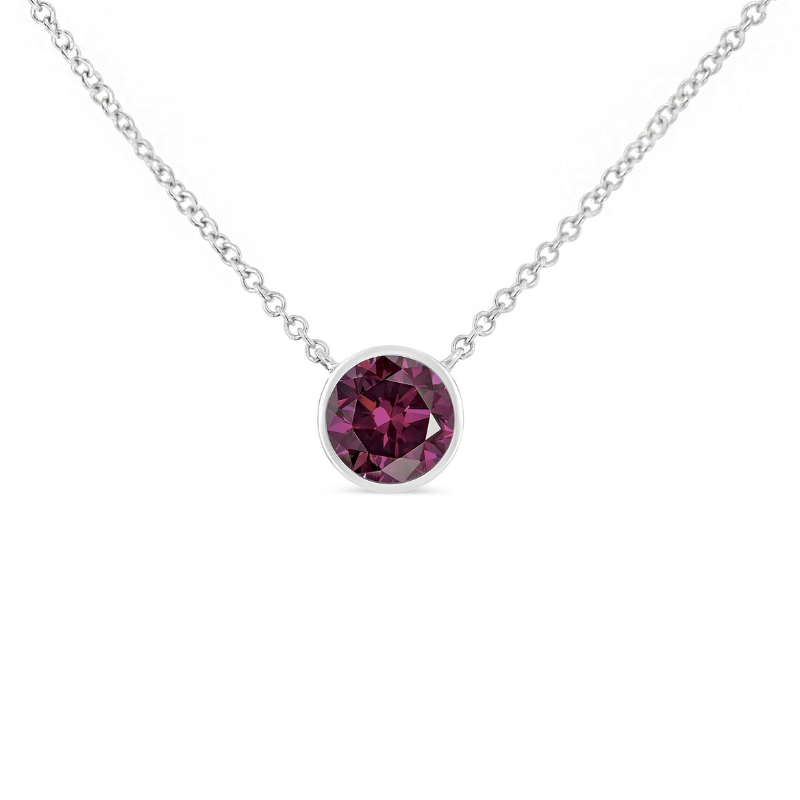 A sterling silver pendant necklace featuring a round, deep purple gemstone set in a bezel setting, attached to a delicate chain.