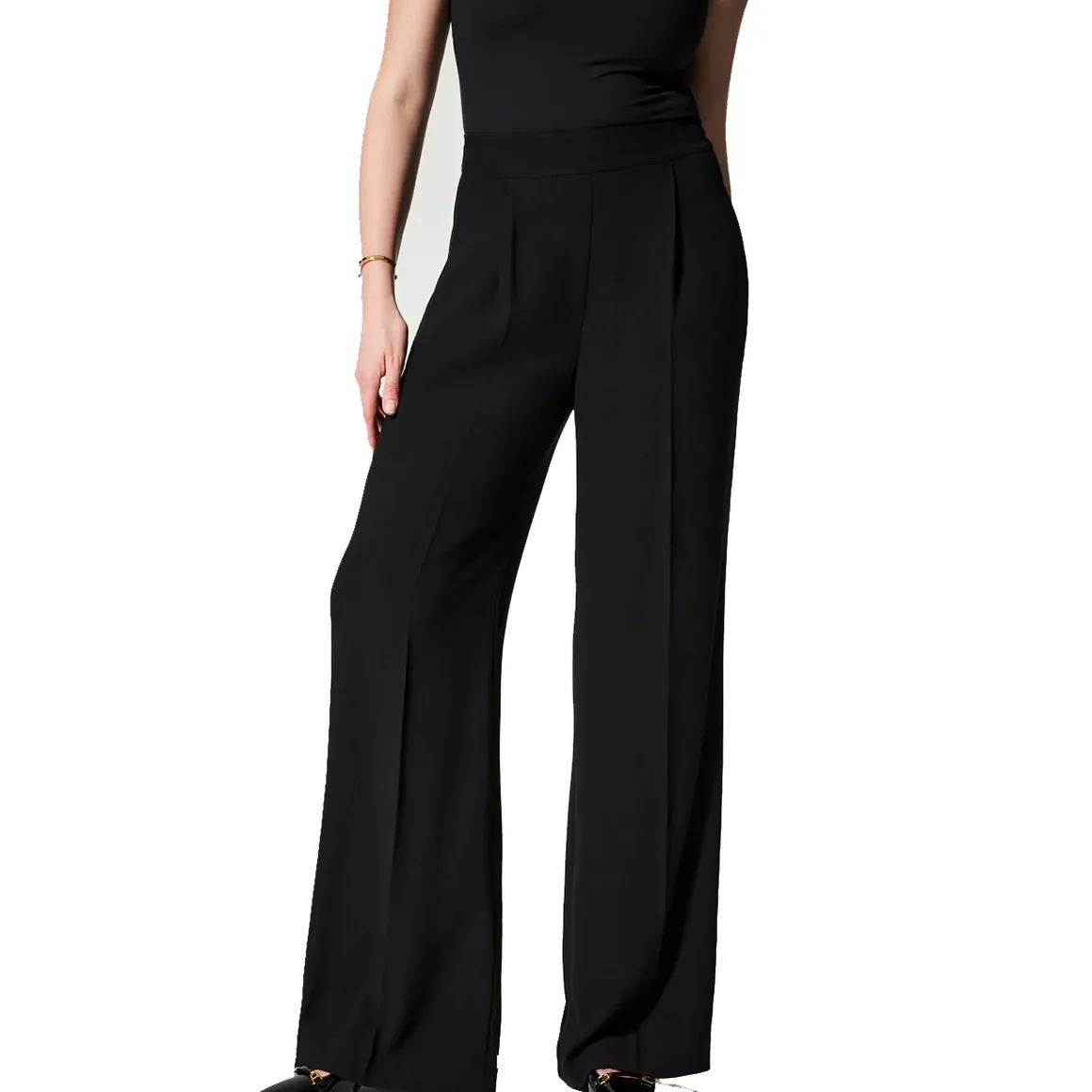 A person is wearing black high-waisted, wide-leg trousers.