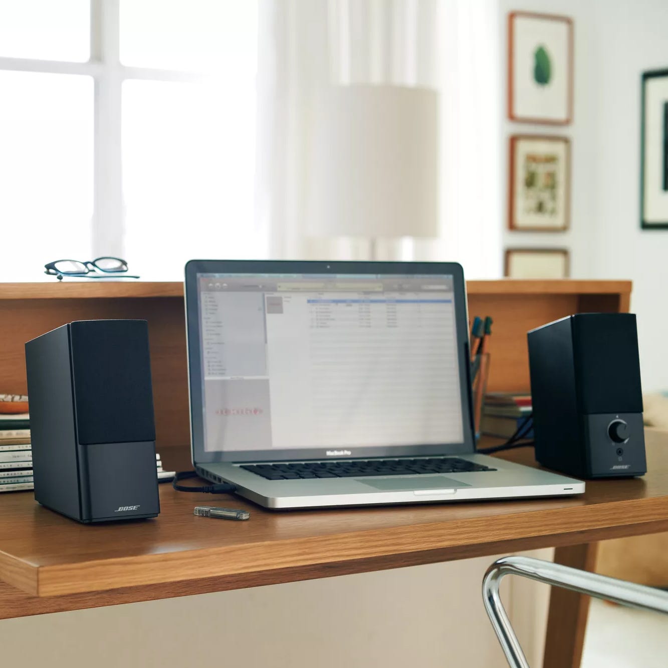 A laptop on a desk flanked by two desktop speakers.