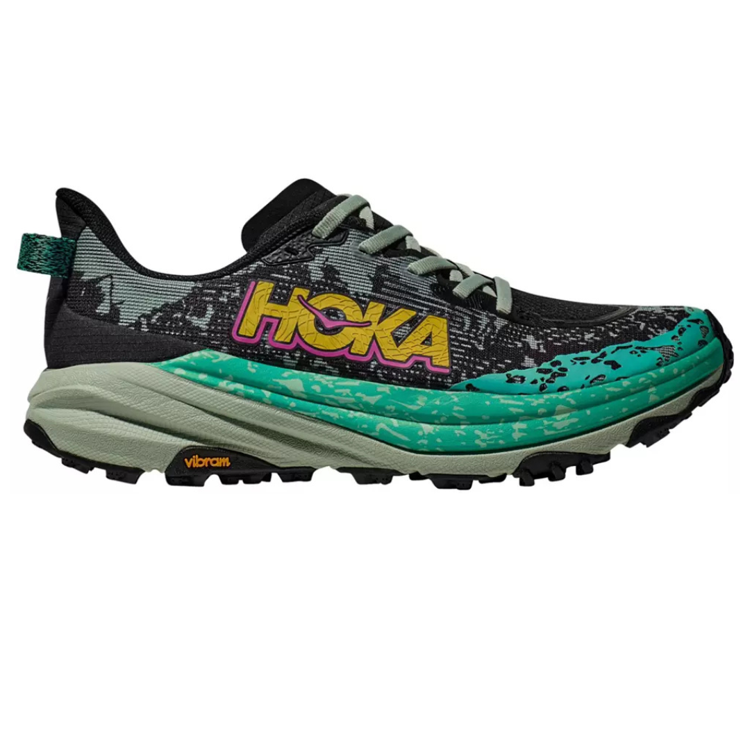 Trail running shoe from HOKA featuring a black upper with teal and green accents, a Vibram sole, and a bold yellow and pink logo.