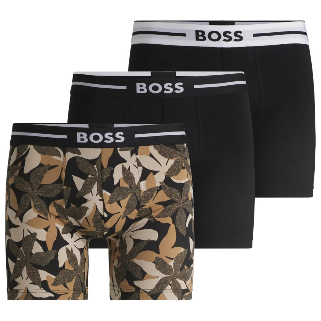 A set of three men's boxer briefs featuring two solid black pairs and one with a foliage pattern, all with \“BOSS\“ branded waistbands.