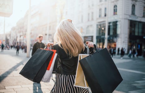 A black friday shopper holds several shopping bags over their sholders