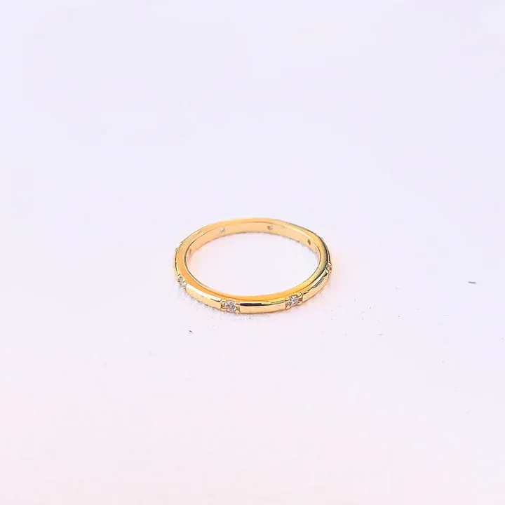 A gold ring with several small diamonds embedded along the top half.