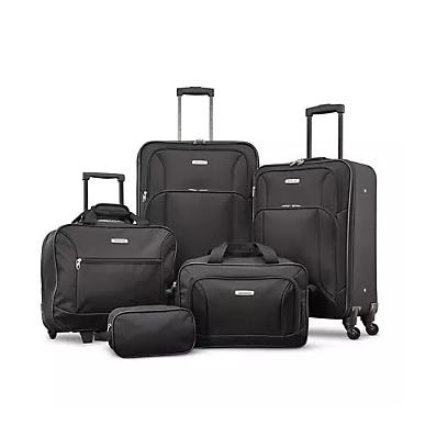 A set of black luggage, including two wheeled suitcases, a travel bag, a duffel, and a toiletry pouch.