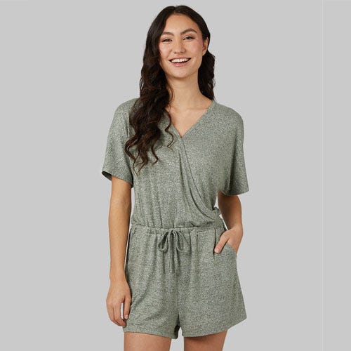 A woman is wearing a green heathered romper with short sleeves, a v-neckline, and a drawstring waist.