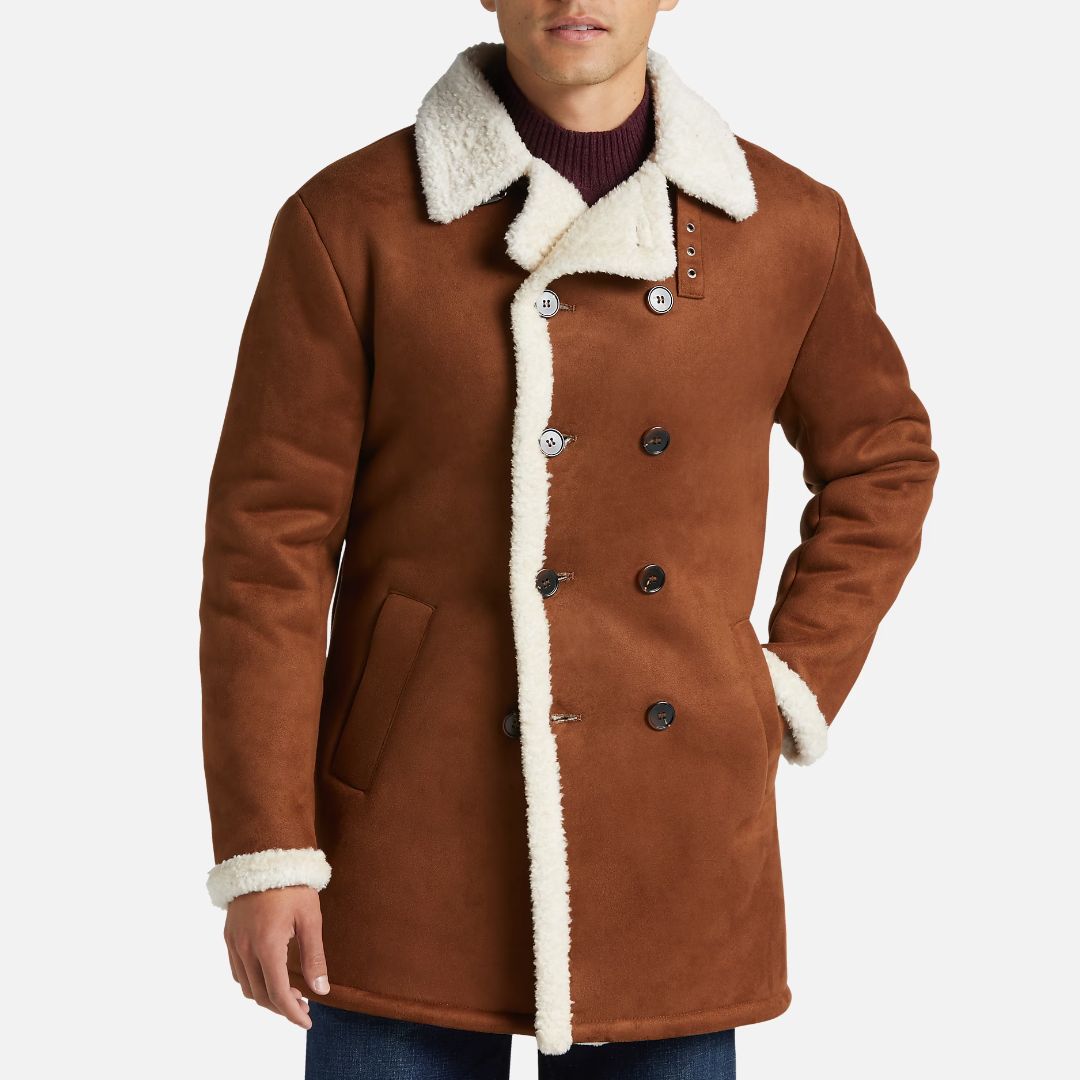 A man wearing a brown shearling coat with white lining and a dark purple sweater.