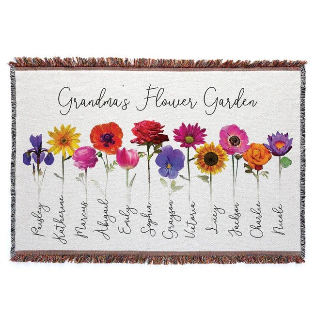 A fringed throw blanket titled \“Grandma's Flower Garden\“ features colorful flowers, each labeled with a different name written in script beneath them, likely representing family members or loved ones.