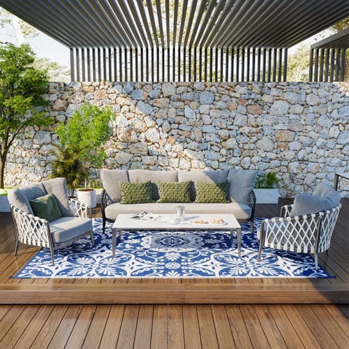 Outdoor patio furniture set with a sofa, two chairs, a coffee table, and a blue and white patterned area rug.