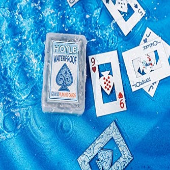 Waterproof playing cards are scattered on a wet surface, with a clear case displaying the “HOYLE Waterproof” brand.