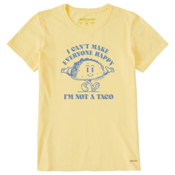 Yellow women's T-shirt featuring a cartoon taco with arms and legs. The text reads \“I CAN'T MAKE EVERYONE HAPPY I'M NOT A TACO\“ in blue, and it's branded with \“Life is Good.\“