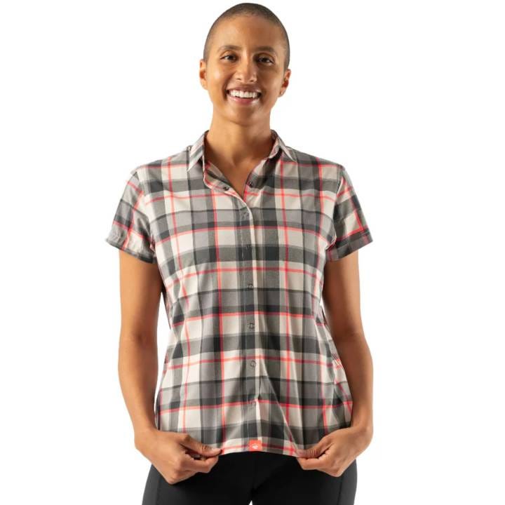 A woman is wearing a short-sleeved plaid shirt with a collar in gray, white, and red tones.