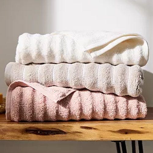 A stack of plush towels in two shades, one in white and the other in light pink.