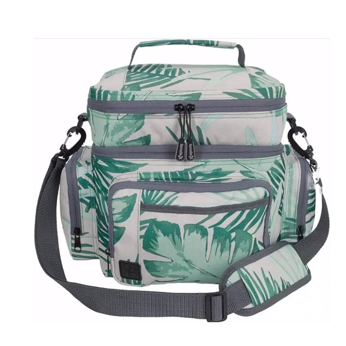 A soft cooler with a shoulder strap and green tropical leaf pattern design, featuring multiple compartments and zippers.