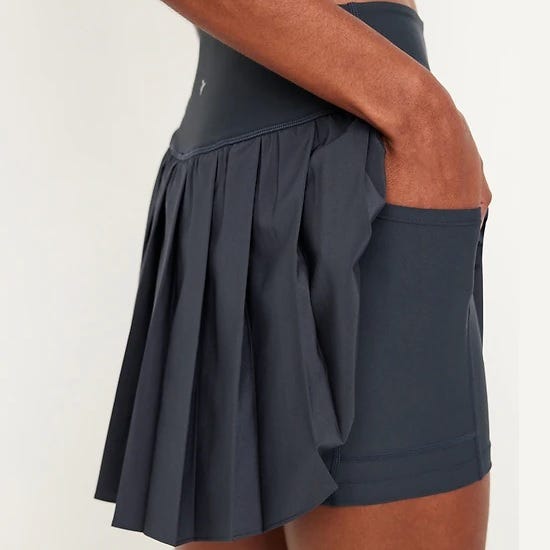 A dark pleated athletic skirt with built-in shorts, featuring a side pocket.