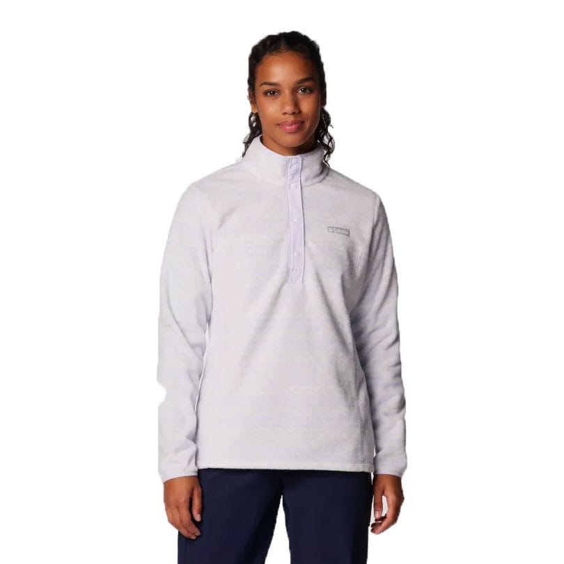 A woman wearing a light gray quarter-button pullover fleece with a high collar, featuring a small logo on the chest, paired with dark pants.