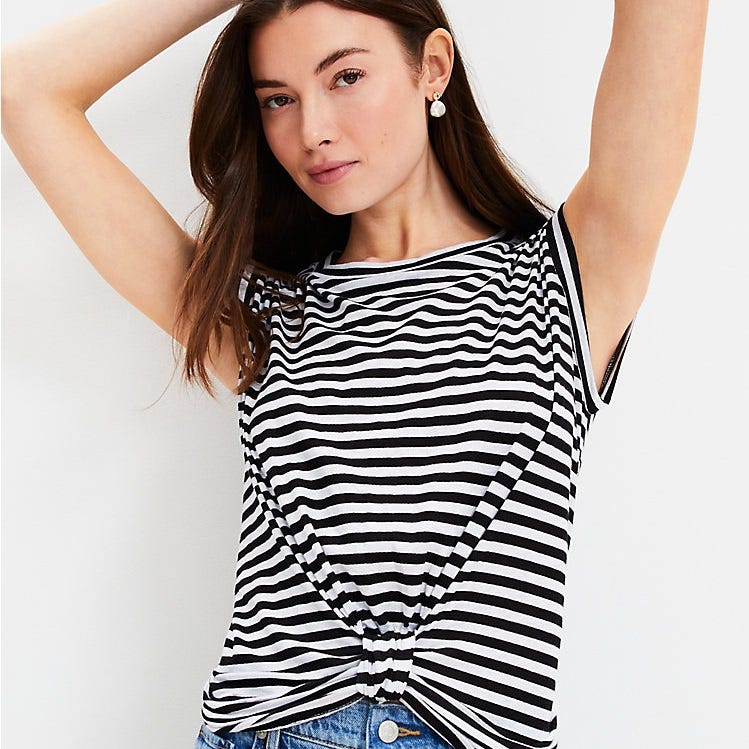 A woman is wearing a black and white striped, short-sleeved top with a tied knot at the waist.