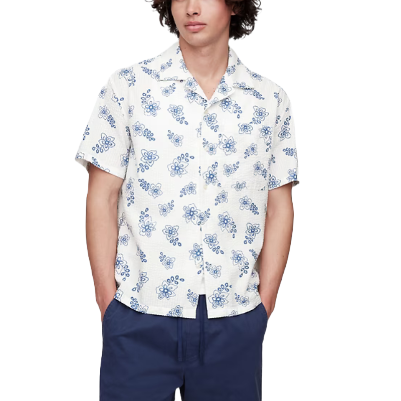 A person is wearing a white short-sleeve button-up shirt with a blue floral pattern, paired with navy blue pants.