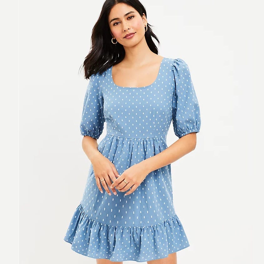 A woman wearing a blue dress with white polka dots and three-quarter sleeves, featuring a ruffled hemline.