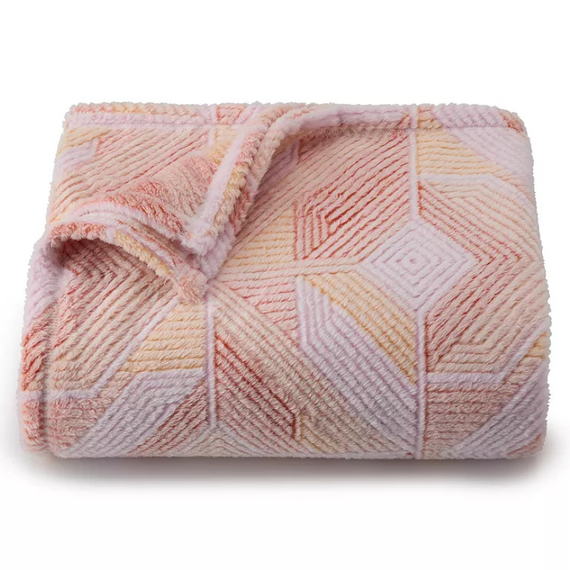 A soft, plush blanket featuring a geometric pattern in shades of pink and peach.