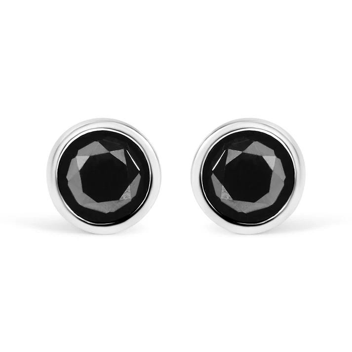 1ct black diamond studs set in a round silver bezel setting. The diamonds have a faceted finish, creating a sleek and elegant appearance.