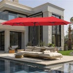 A red outdoor parasol shades a patio sectional sofa beside a pool, with a modern house in the background.