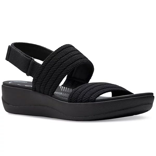 Black sandal with a low wedge heel and textured fabric straps, including an adjustable back strap for support.