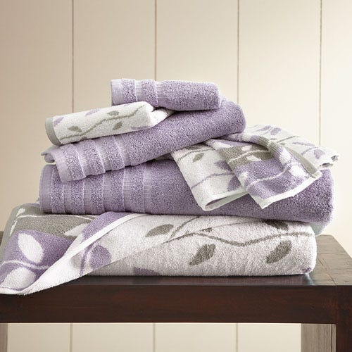 A stack of purple and white patterned towels on a wooden surface.