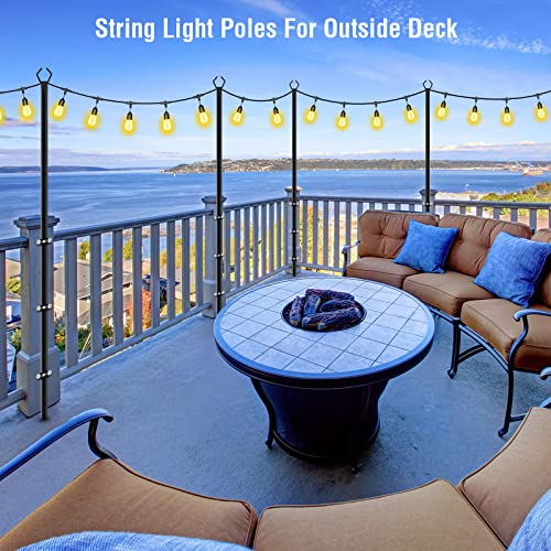 Two black poles, approximately 10 feet high, support a string of spherical lights across a patio with outdoor furniture overlooking a scenic view.