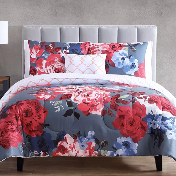 A floral patterned bedding set with a comforter and pillows in shades of red, blue, and white.