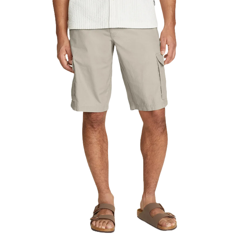 A person is wearing beige cargo shorts and brown slide sandals. The sandals have two adjustable straps and a cork footbed.